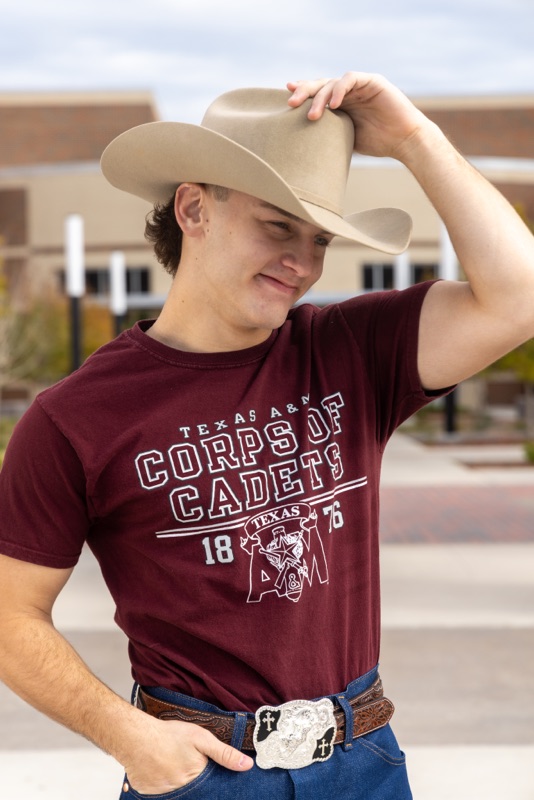 Young man tipping a cowboy hat, wearing a Texas A&M Corps of Cadets T-shirt
